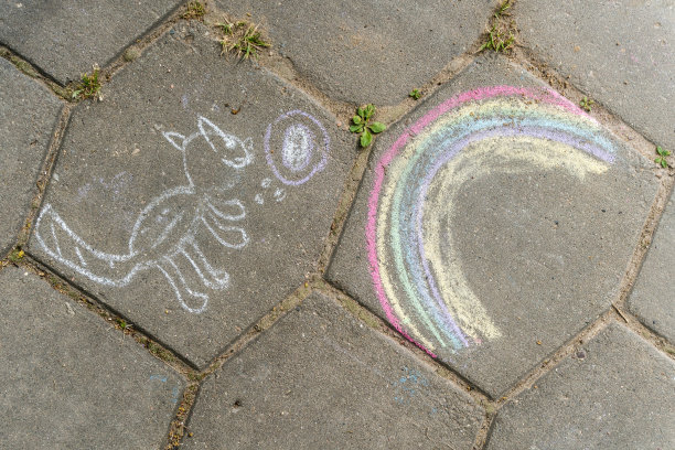 孩子们用粉笔在沥青上画画。猫和彩虹。图片下载