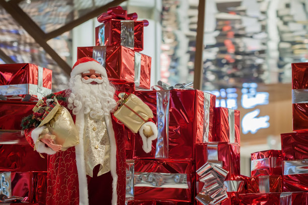 又大又快乐的圣诞老人娃娃和许多带着彩带的红色礼盒。圣诞背景、礼物、购物理念。丰富的圣诞图片下载