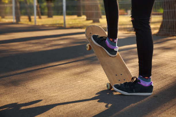 一个穿着运动鞋玩滑板的女孩的腿在滑板上变了个花样。图片下载