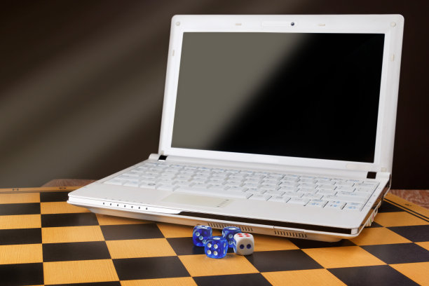 笔记本电脑的空白屏幕和木棋盘上的骰子图片下载