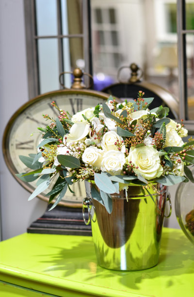 背景是绿色桌子上闪亮的金属桶里的一束玫瑰图片下载