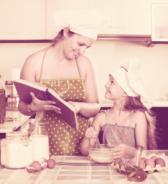 快乐的妈妈向女孩展示煎蛋卷的食谱图片下载