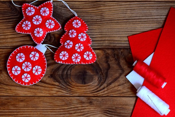 简易圣诞工艺品装饰。毛毡星，圣诞树和球在一个棕色的木制背景与copyspace。缝纫车间的概念。为孩子们制作圣诞工艺品。俯视图图片下载