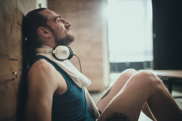 在健身房更衣室放松的快乐运动员的侧面视图。图片下载