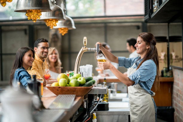 快乐的酒保在酒吧提供啤酒素材图片