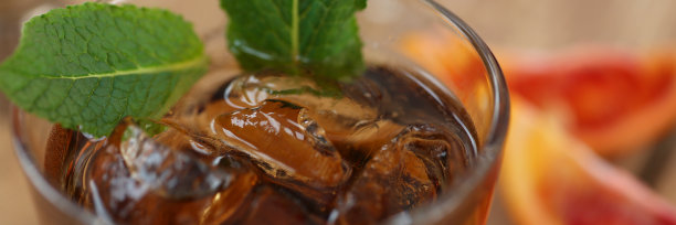 鸡尾酒威士忌可乐加冰在玻璃杯中。木板上放着水果的碎片。照片景深。图片下载