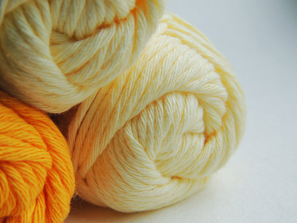 白色、奶油色和黄色的棉线球，用于编织和钩编。图片下载