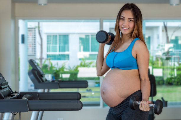 肖像亚洲孕妇在运动室内做运动，举哑铃，健康母亲的概念图片下载