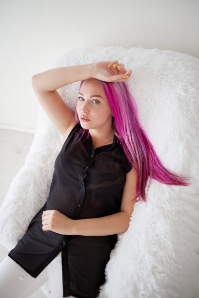 那个长着粉红色头发的女孩正坐在一张白色扶手椅上图片下载