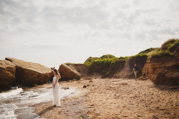 海边的户外沙滩婚礼，时尚快乐的新郎带着婚礼花束向新娘走来图片下载
