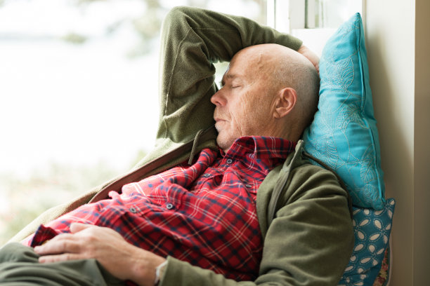 年长的男子闭着眼睛坐在靠窗的座位上休息图片下载