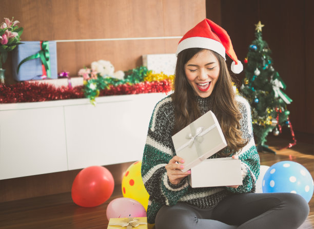 年轻快乐的亚洲女人与圣诞老人帽惊喜和持有礼物盒礼物圣诞派对和庆祝，圣诞快乐和新年的概念图片下载