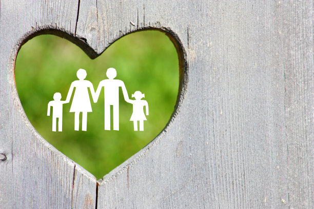 家庭在木制的背景与绿色的心图片下载