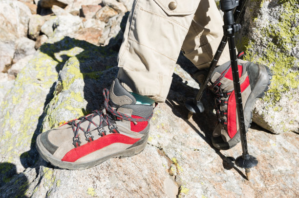 特写的女性腿在徒步靴与棍棒北欧人走在岩石和遥远的高加索土地的背景图片下载