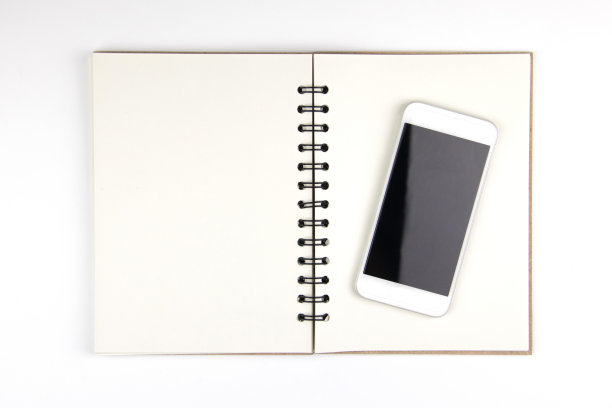 在白色孤立的背景上的空白书上的手机的顶角视图图片下载