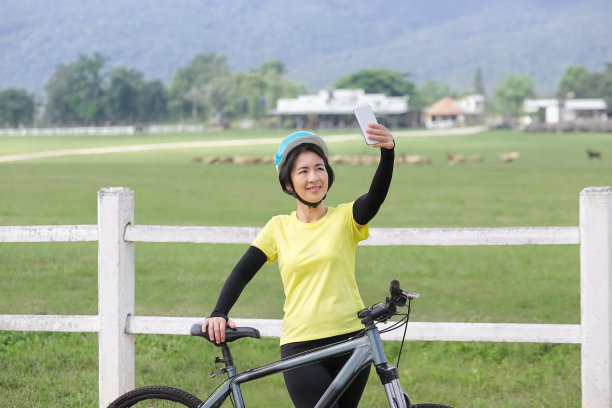 中年妇女在自行车上用手机自拍图片下载