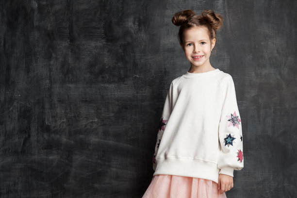 可爱的小女孩微笑着看着相机，站在学校黑板的背景上，还有空间图片下载