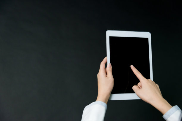 在黑色背景上手持数码平板电脑的女商人素材图片