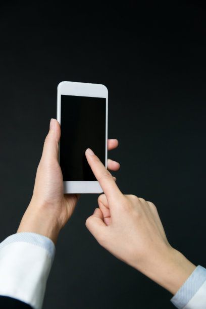 一个女人在黑色背景下拿着智能手机素材图片