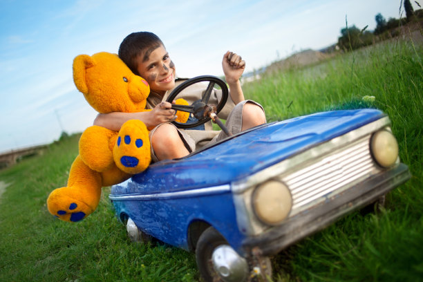 一个小男孩开着一辆老式玩具车，阳光明媚图片下载
