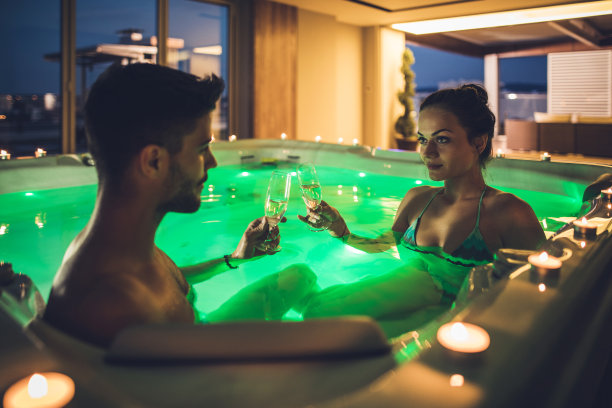 年轻夫妇在热浴盆里喝着香槟敬酒。图片下载