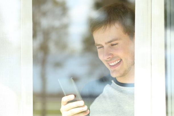 透过窗户看到一个男人在用智能手机图片下载