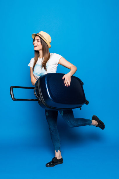 蓝色背景下的女人准备好夏季旅行了。蓝色背景上背着行李跑的漂亮女人图片下载