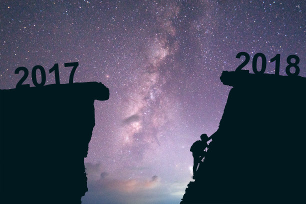 2017年至2018年间，年轻人在攀登。新年快乐2018概念银河系背景图片下载
