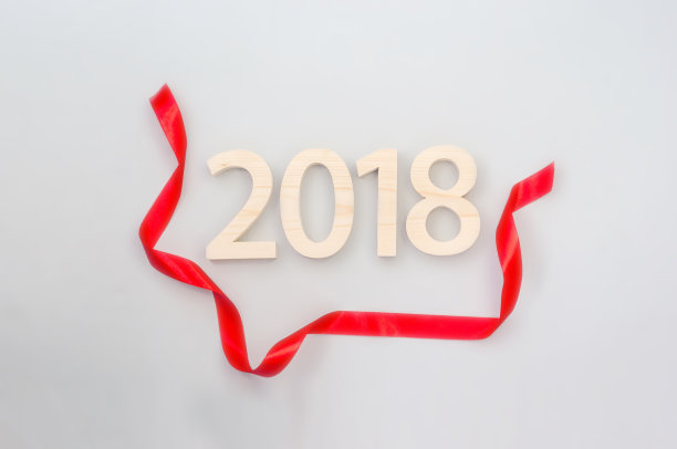 木制人物形成2018年，由浅木雕刻在灰色的背景和红色的丝带。新年想法，明信片，海报，问候。节日的装饰。图片下载