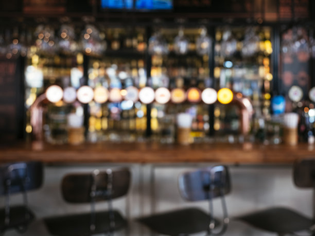 吧台与座位凳子啤酒标签模糊酒吧背景图片下载