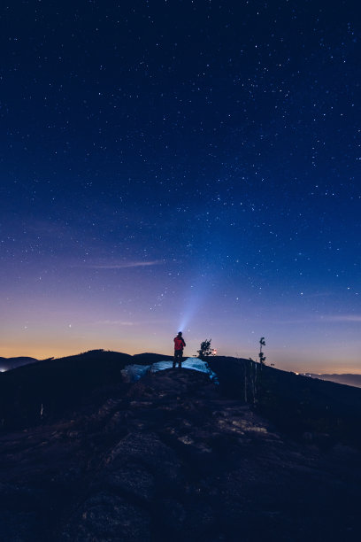 一个人用他的手电筒把光指向天空。图片下载