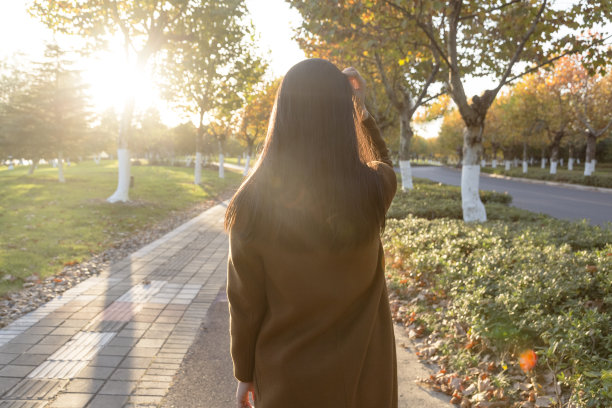 一幅年轻女子靠树站在公园里的肖像图片下载