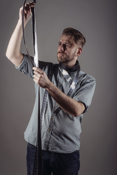 赶时髦的人在灰色背景上看捕获的胶片的质量图片下载