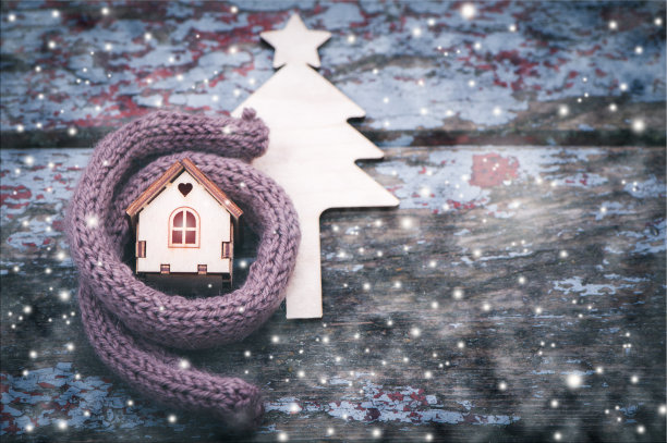 玩具屋裹着一条暖和的围巾，正在下雪。背景是一棵皮草树。图片下载