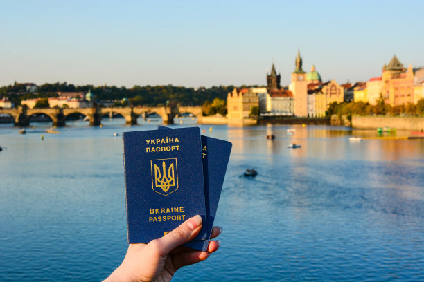 一名女子手握两本乌克兰护照，眼前是布拉格古城的城市风光图片下载
