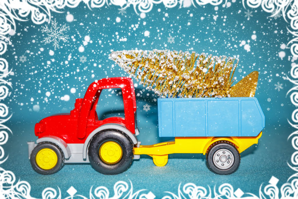 圣诞庆祝节日主题。拖拉机载着圣诞树在拖车在下雪的背景。雪花和圣诞玩具。新年的概念图片下载
