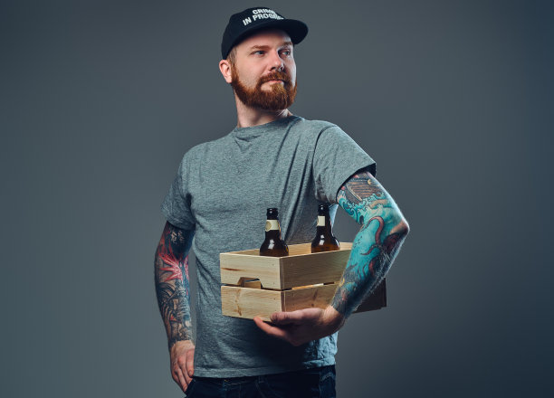 一个男人拿着一个装着啤酒瓶的木箱。图片下载