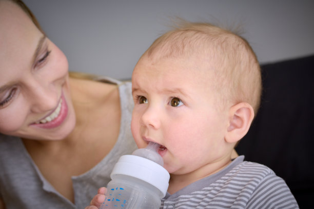 沉思的婴儿从瓶子里吃东西图片下载