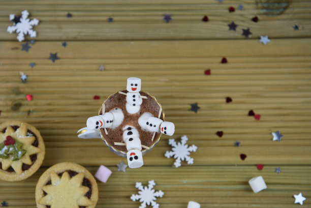 圣诞食物和饮料的照片，一杯热巧克力和迷你棉花糖形状的快乐雪人的微笑，传统的水果馅饼洒上小心星和雪花图片下载