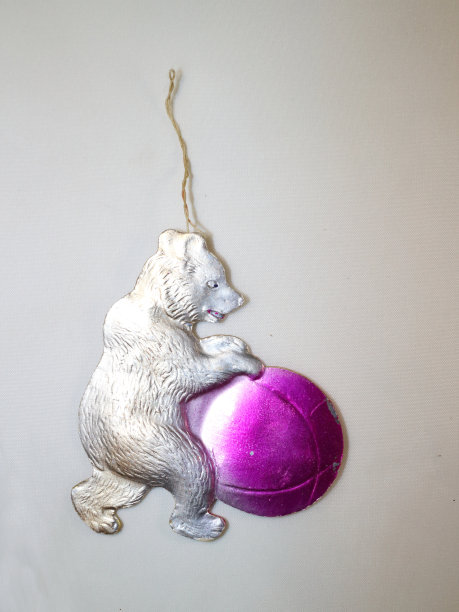 一棵圣诞树，一个纸板做的旧玩具，一只爪子里叼着粉红球的银色熊图片下载