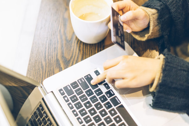 年轻女子在咖啡馆用信用卡和笔记本电脑素材图片