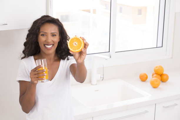 女人展示了一半的橙色水果。橙汁和水果概念。素材图片