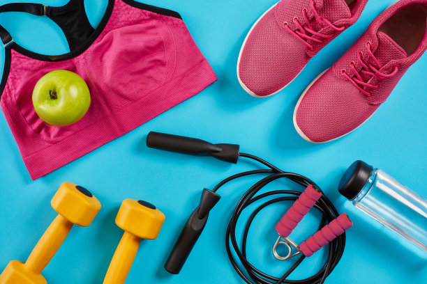 运动员套装，女性服装，哑铃和水瓶在亮蓝色的背景图片下载
