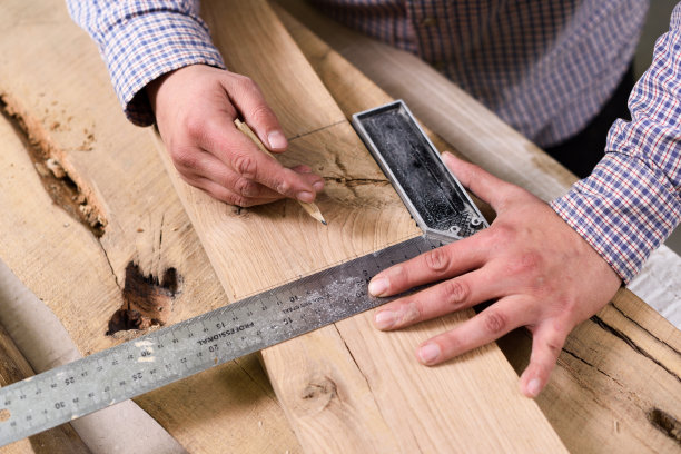 木匠在起作用。人们用金属尺和铅笔测量木板并做记号图片下载