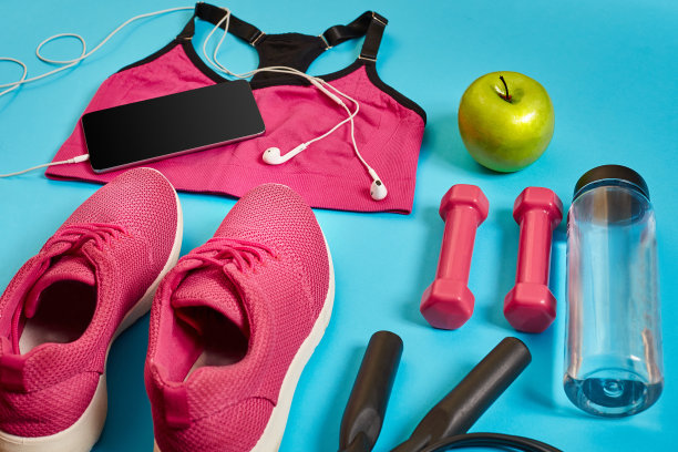 运动员套装，女性服装，哑铃和水瓶在亮蓝色的背景图片下载