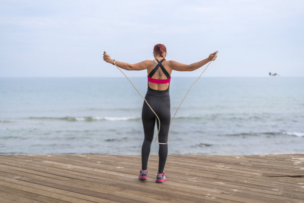 适合年轻女子跳上一根绳子附近的海景图片下载