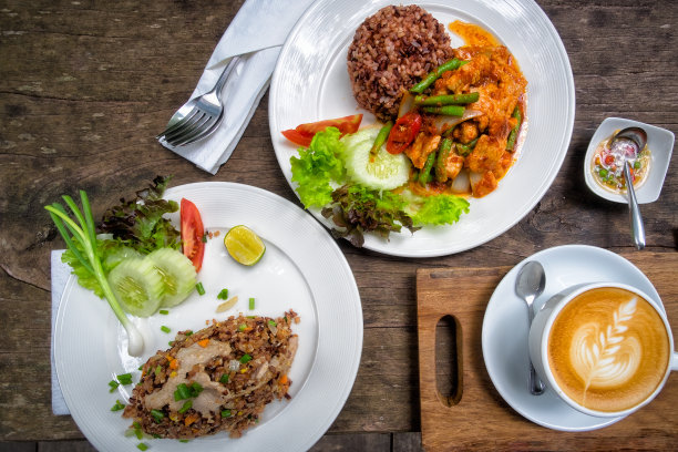 猪肉炒辣椒酱，肉炒饭，炒饭和热拿铁咖啡放在木桌上。图片下载