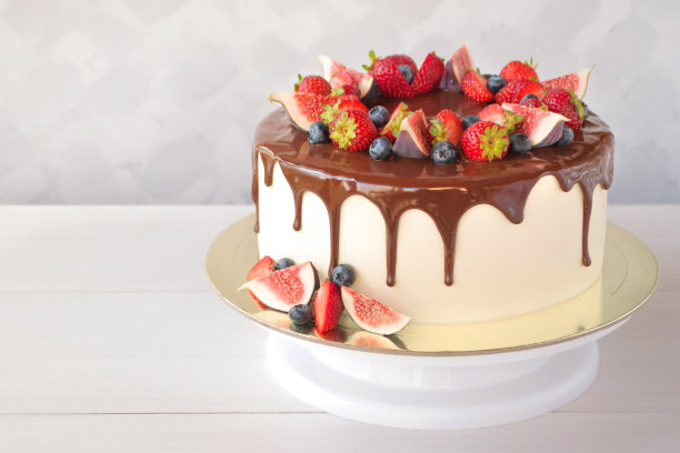 巧克力蛋糕，用草莓、蓝莓和无花果片装饰在白色的木桌上，迎接清晨的阳光。图片下载