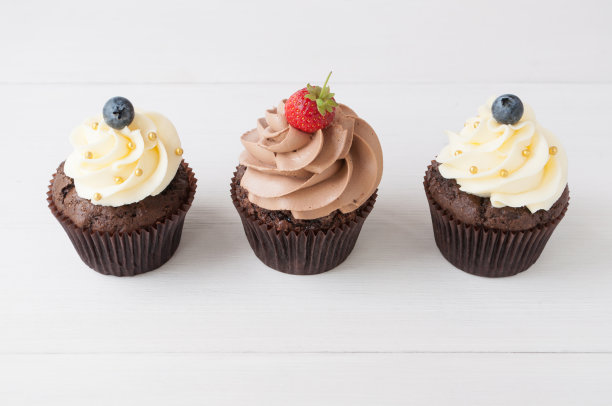 白色木桌上点缀着新鲜草莓、蓝莓和金色的巧克力蛋糕。图片下载