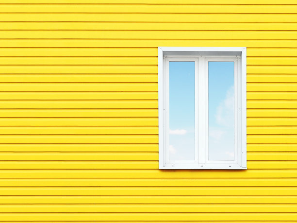 黄色墙板上的白色塑料窗户。图片与文字空间。图片下载